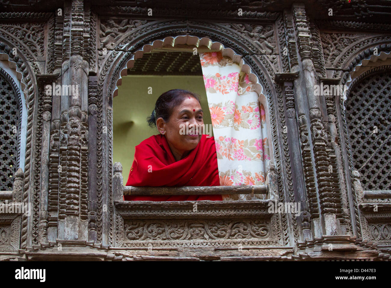 Woman in the window of her old house, Panauti village, near Kathmandu, Nepal Stock Photo