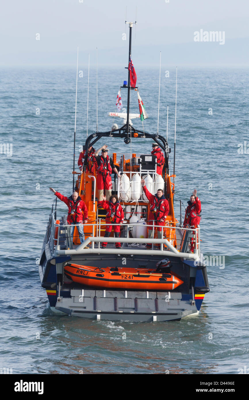 Moelfre, Isle of Anglesey, Wales, UK, Mon 4th March 2013. RNLI lifeboat crew wave to the welcoming crowd whilst showing the Y boat behind the rear transom door on the new £2.7 million Tamar class vessel 'Kiwi' funded by the bequest of a New Zealand seaman Reginald James Clark. The bigger and safer boat replaces the Tyne class vessel which has been in service since 1988. Stock Photo