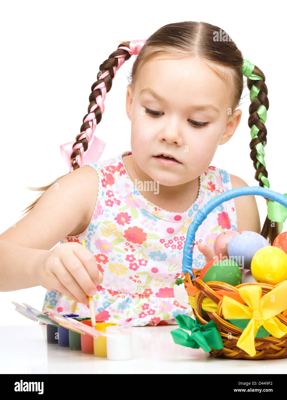 Little girl is painting eggs preparing for Easter, isolated over white