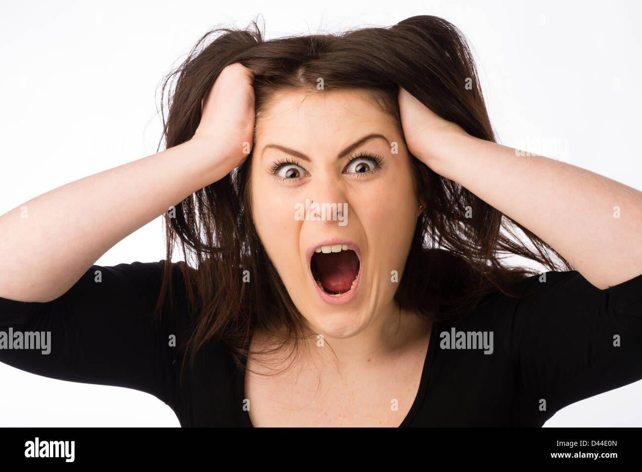 A young angry shouting woman, tearing out pulling her brown hair out , UK Stock Photo