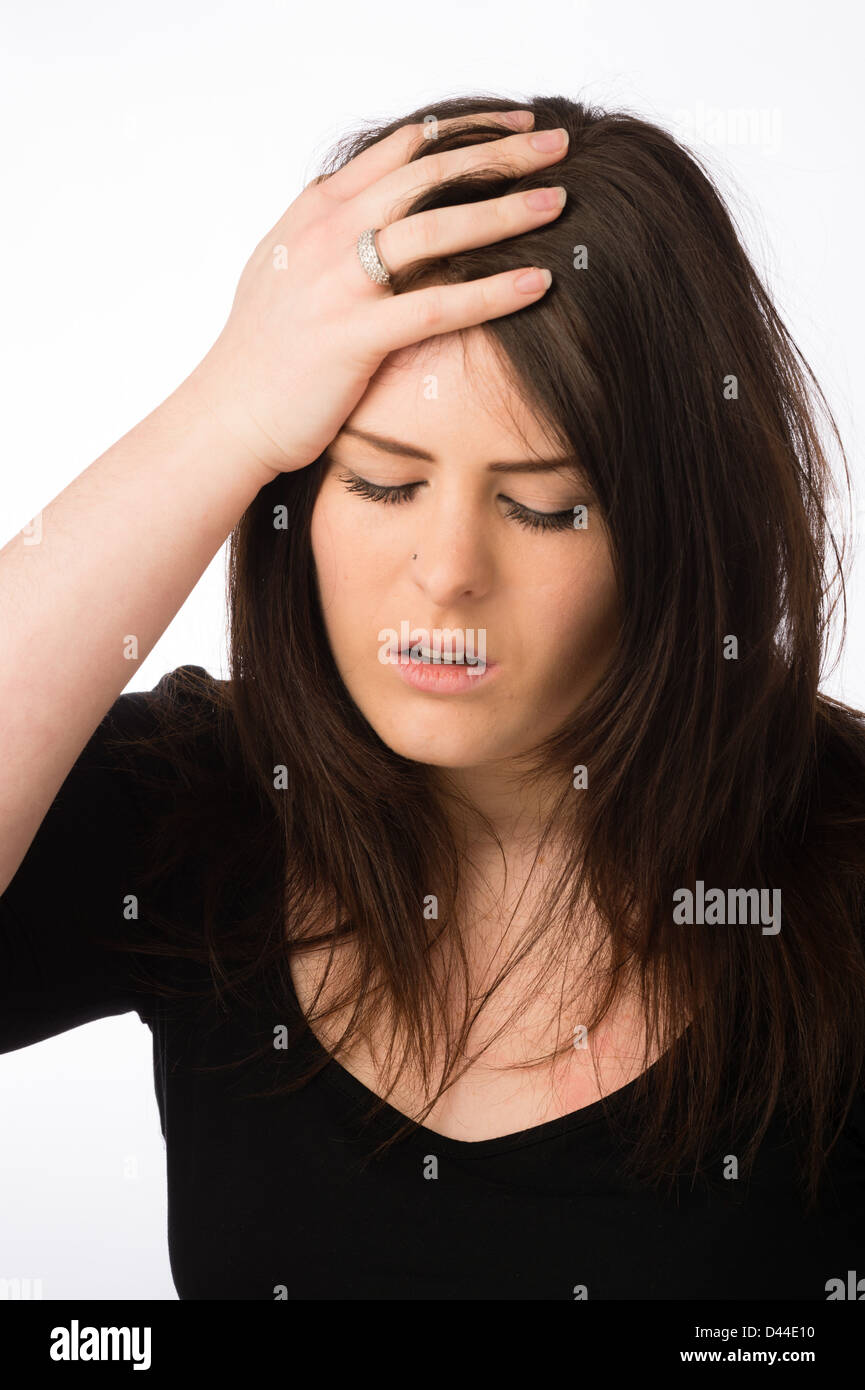 A young ill sick ailing woman, brown hair, hand on her forehead UK Stock Photo