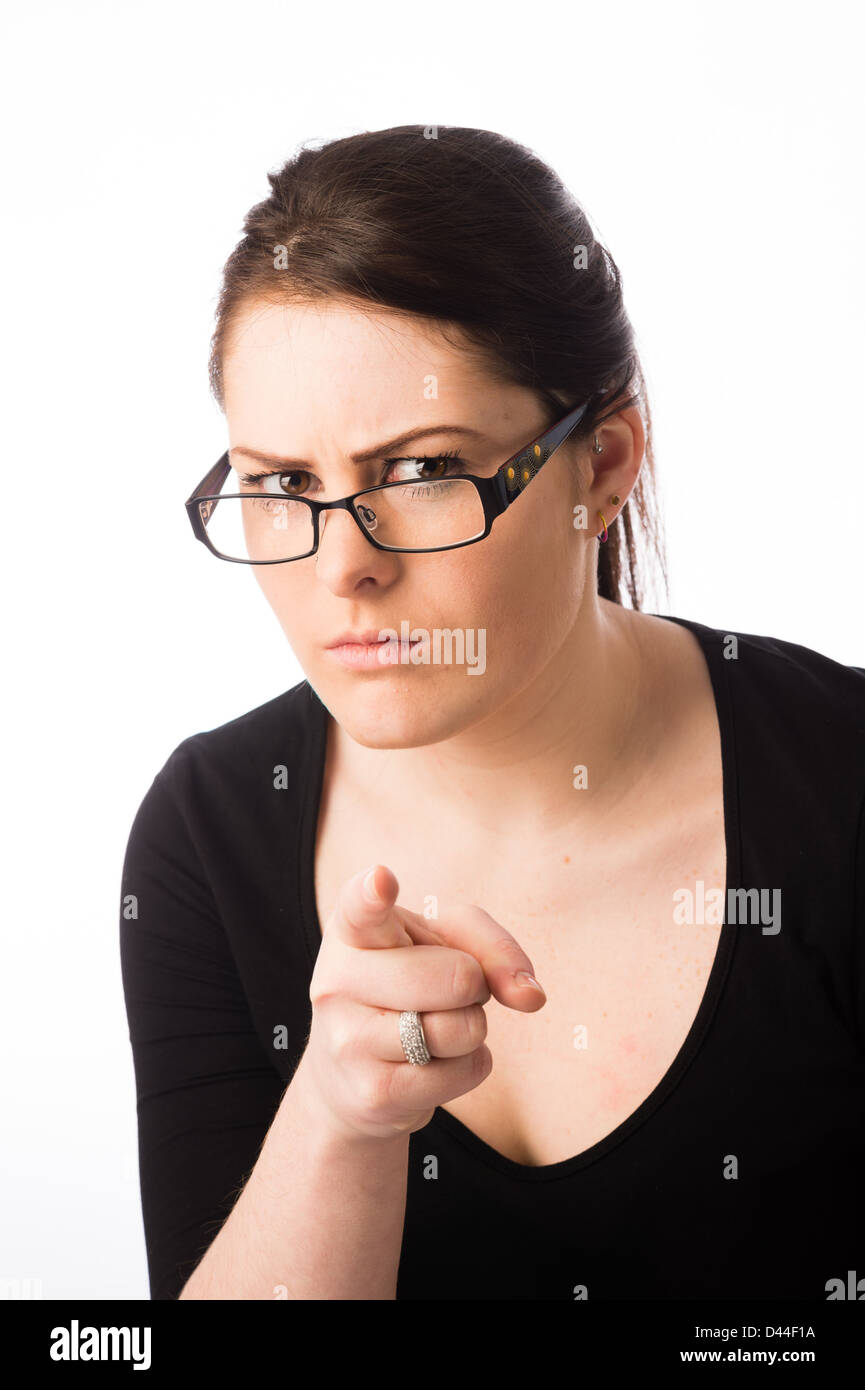 A young stern looking woman, brown hair, wearing spectacles glasses pointing hger finger accusingly UK Stock Photo