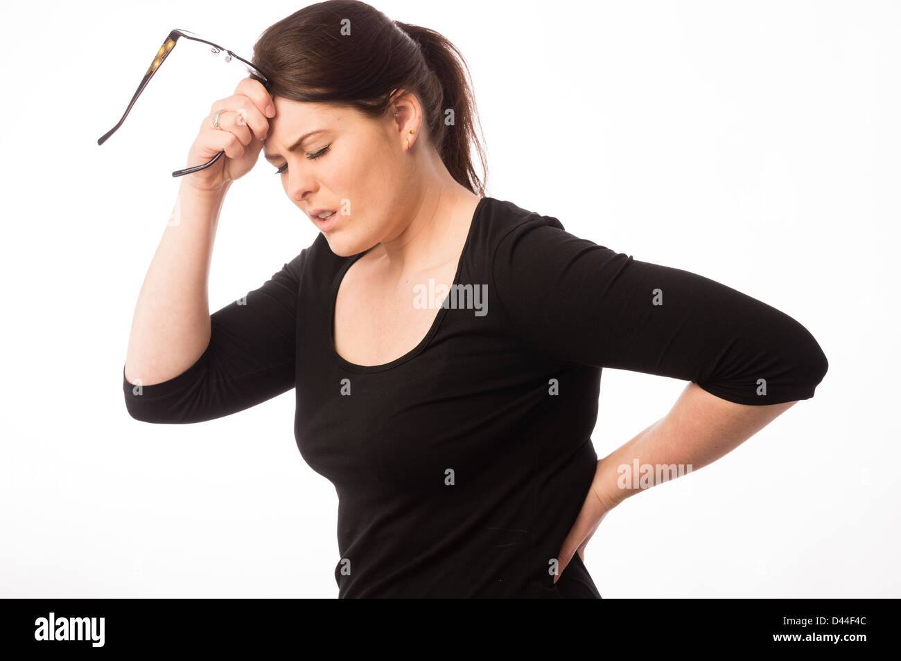 A young woman, brown hair, suffering back pain, tension stress  UK, Stock Photo
