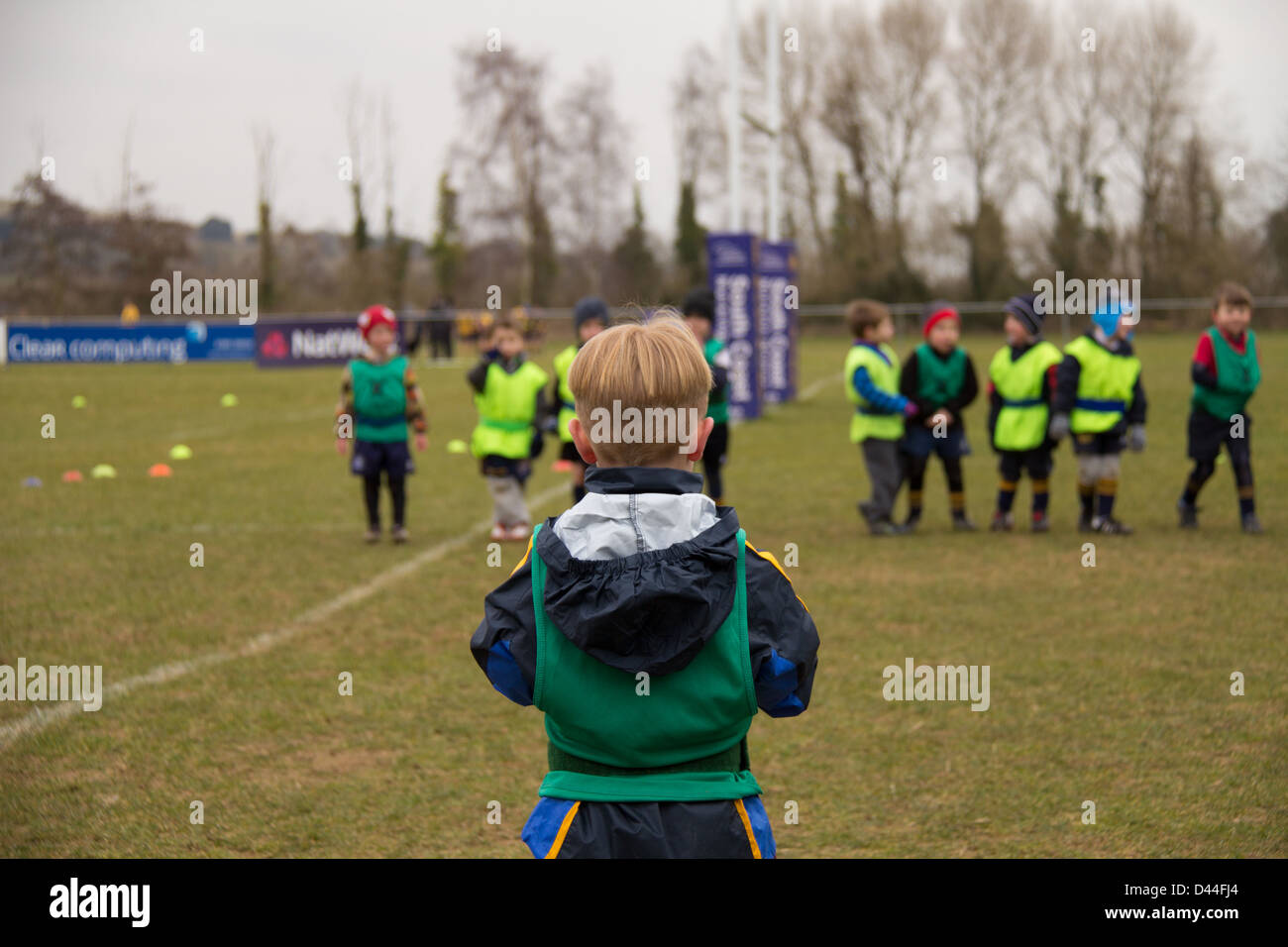 A young boy waiting to confront the challenge of running past a wall of other children to win his rugby competition Stock Photo