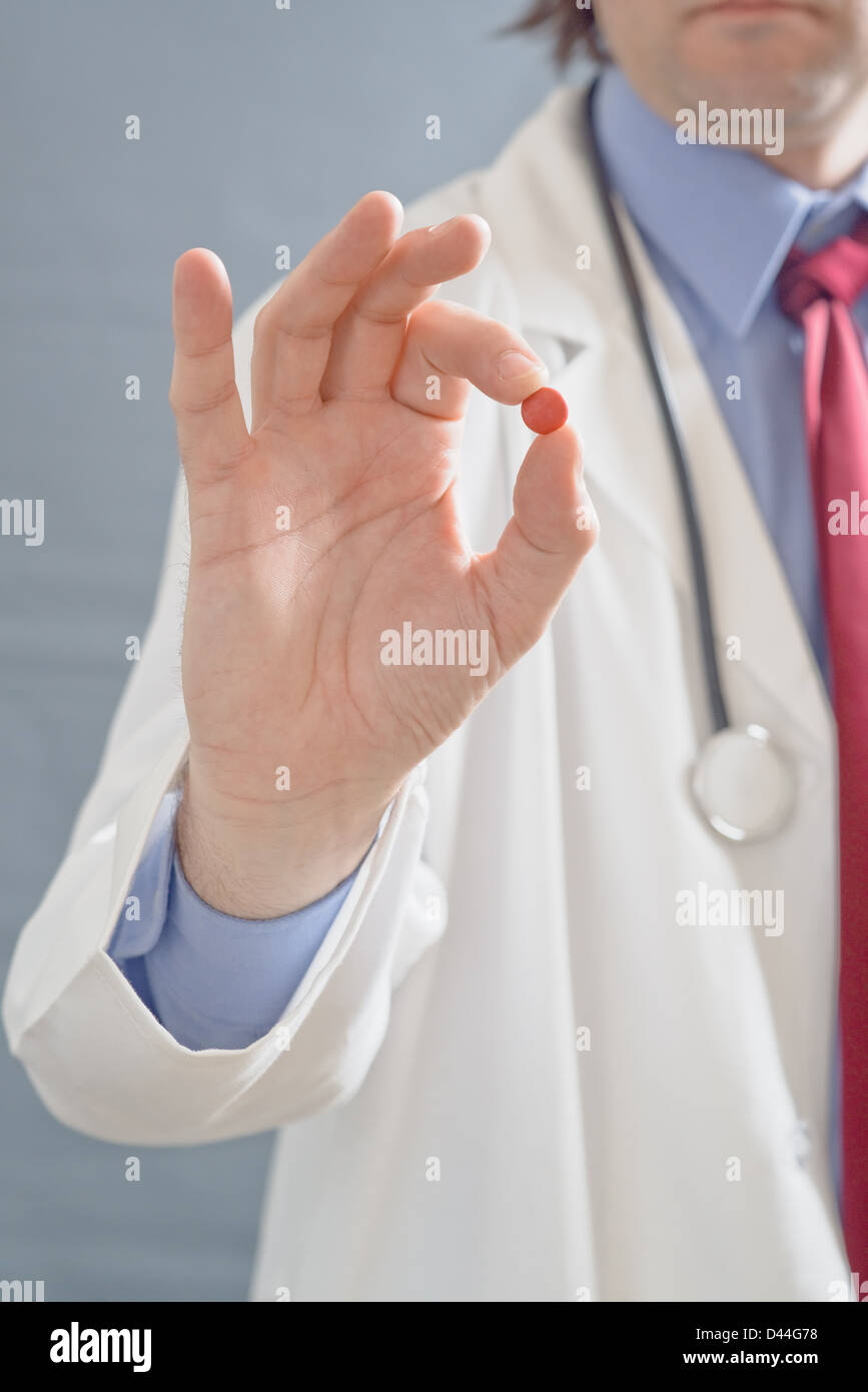 Male doctor holding a pill, close up image with shallow depth of filed with focus on hand with a cure. Stock Photo