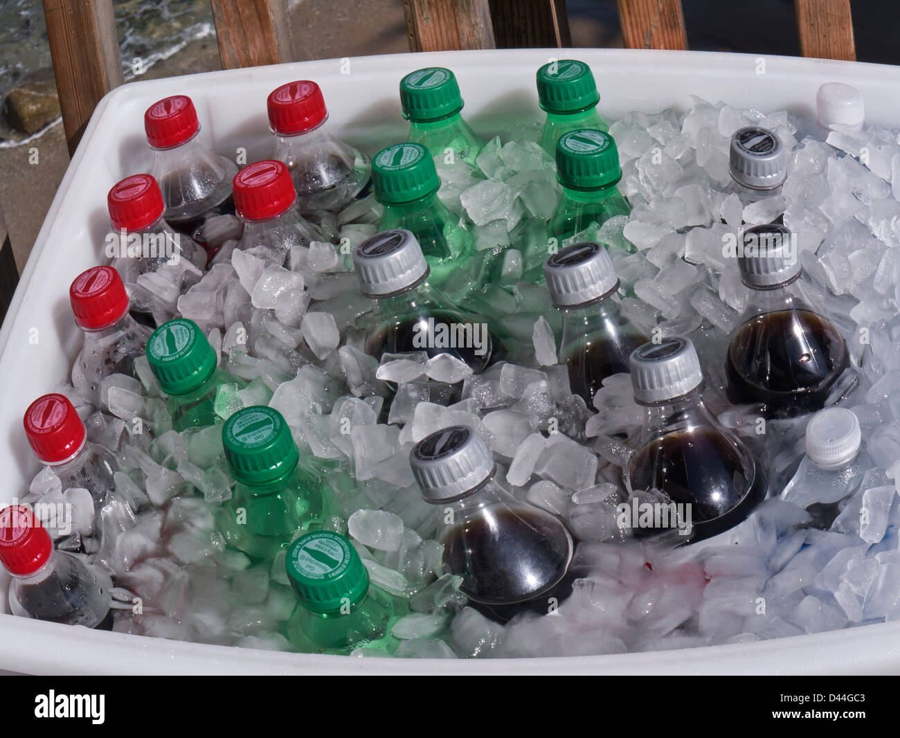 Plastic screw cap Cola soft drink bottles on ice for sale outdoors by street vendor on a sunny day Stock Photo