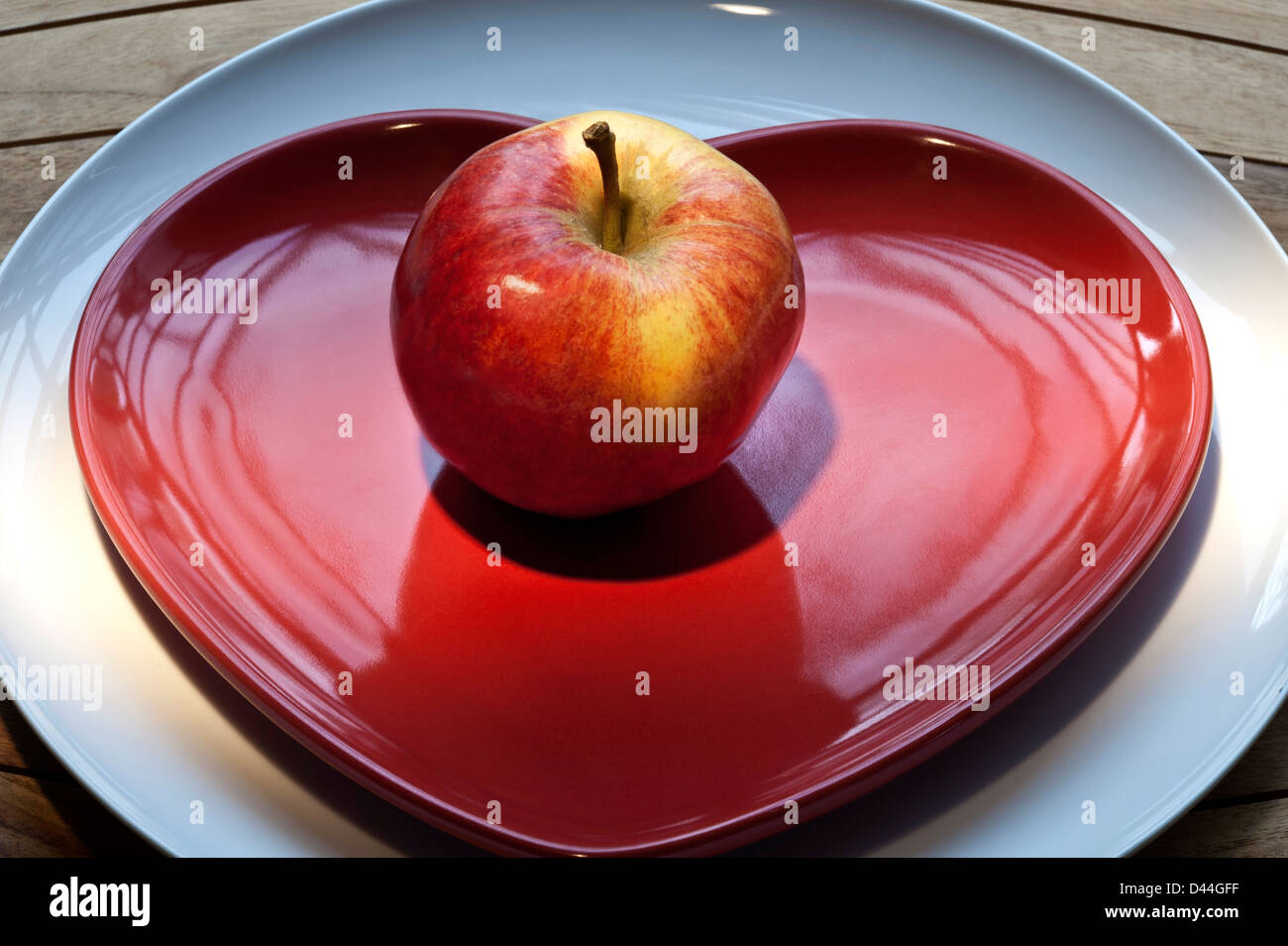 Gala apple on red heart shaped plate, healthy fresh eating regime concept Stock Photo