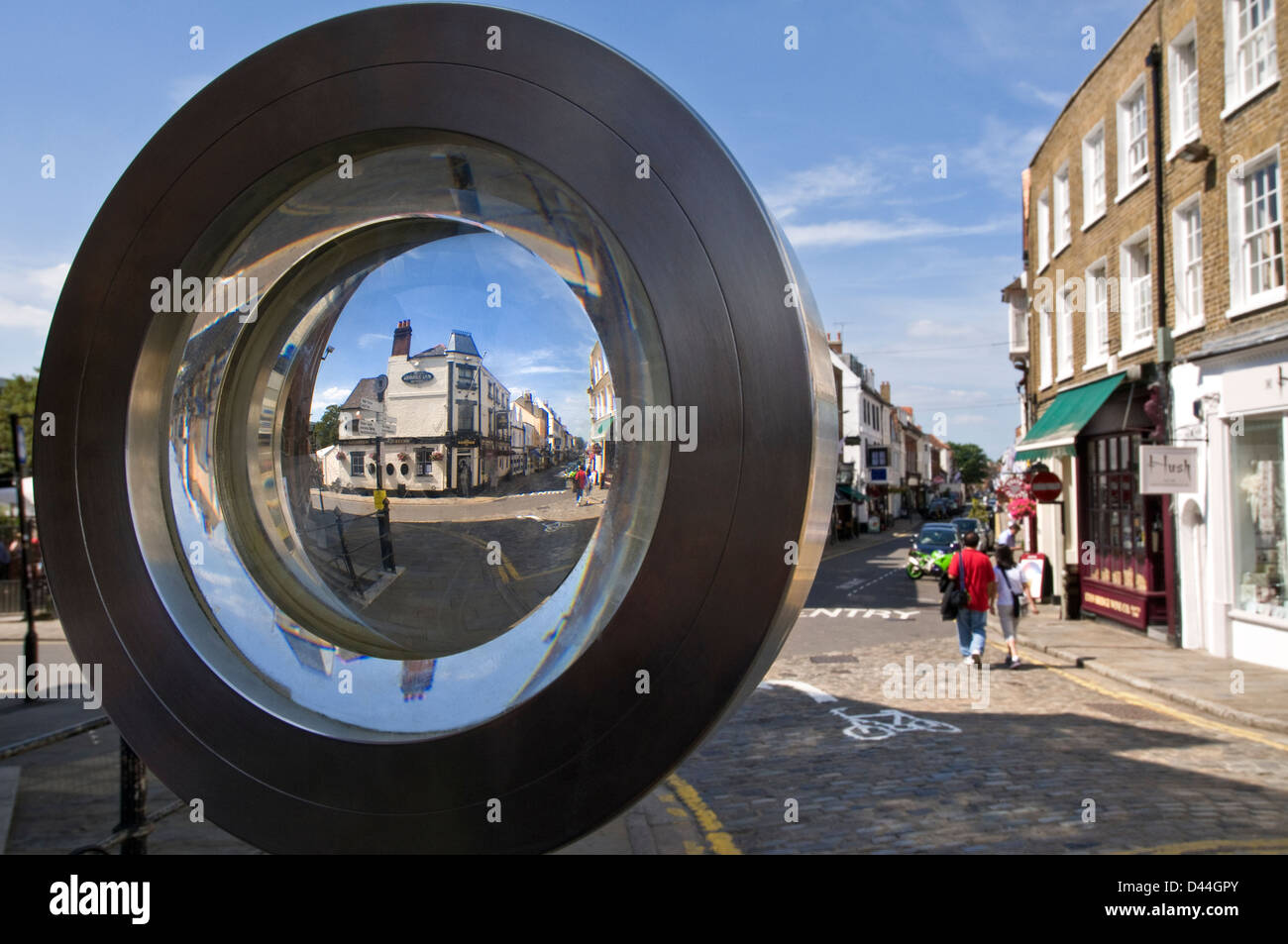 Public sculpture of wide lens glass with view through to Eton High Street and shoppers Eaton Berkshire UK Stock Photo