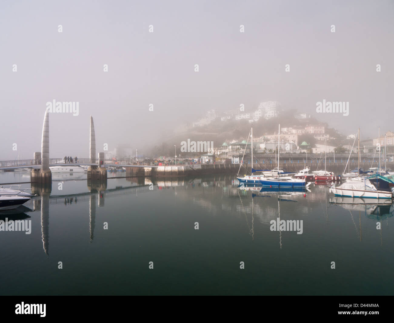 View of Torquay harbour on a still, morning, with sea mist shrouding the buildings. Stock Photo
