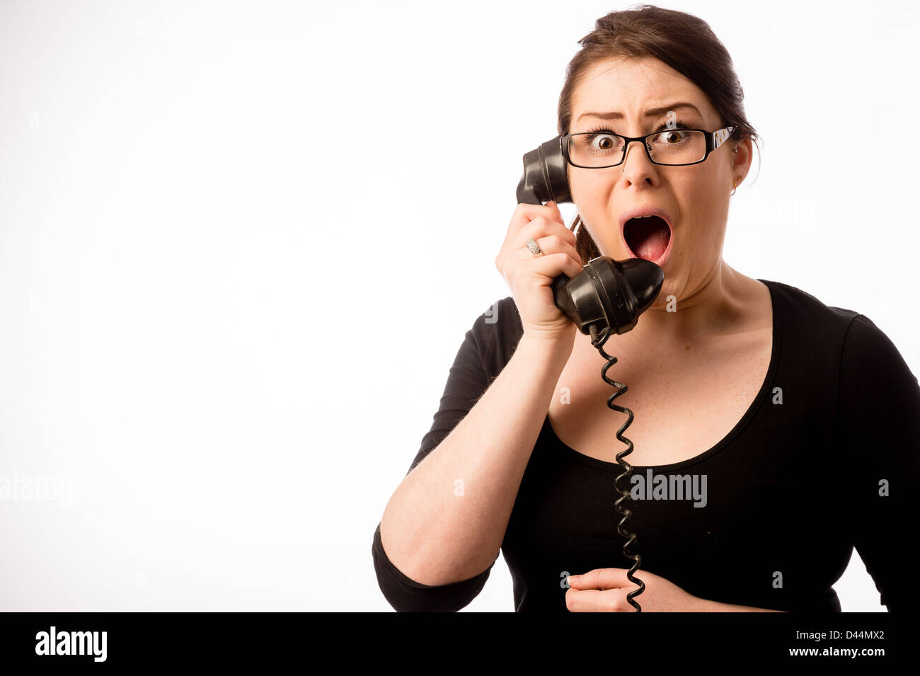 A young woman, brown hair looking shocked, holding an old fashioned telephone, UK Stock Photo