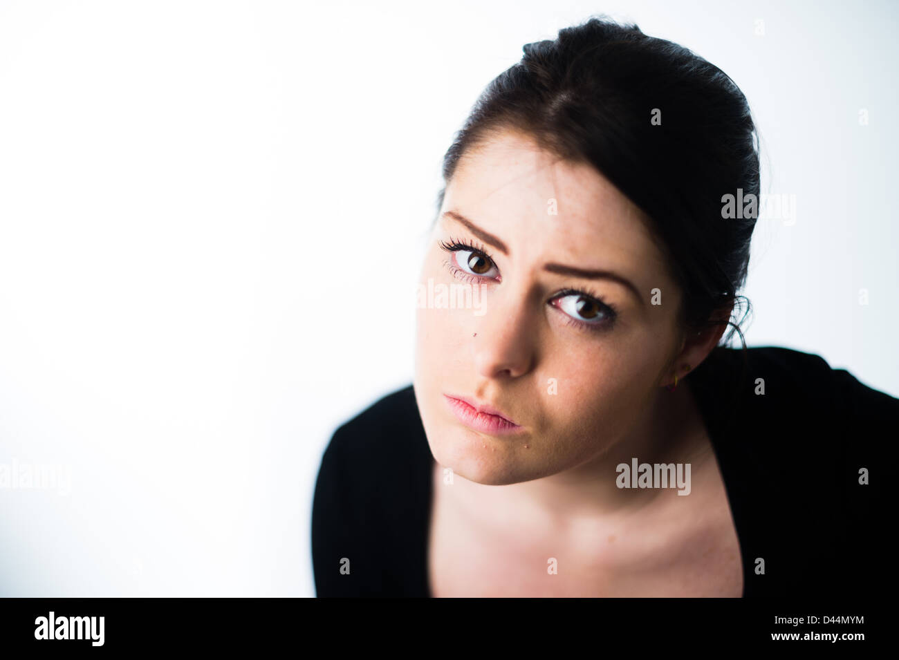 A young woman, brown hair, sitting alone, looking sad down depressed lonely UK Stock Photo