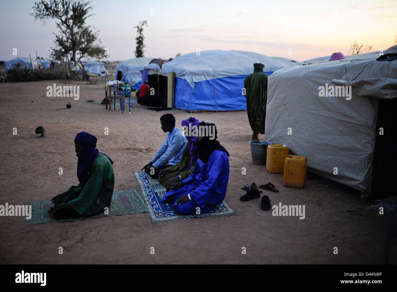 BURKINA FASO Djibo, malian refugees, mostly Touareg, in refugee camp Mentao of UNHCR, they fled due to war and islamist terror in Mali, muslim Touareg men have a prayer to Allah on a carpet facing Mecca, wearing Tagelmust and Boubou Stock Photo