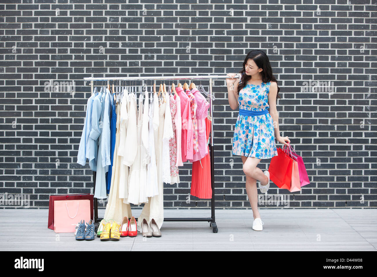 a girl with a shopping bag next to a clothing rack Stock Photo Alamy
