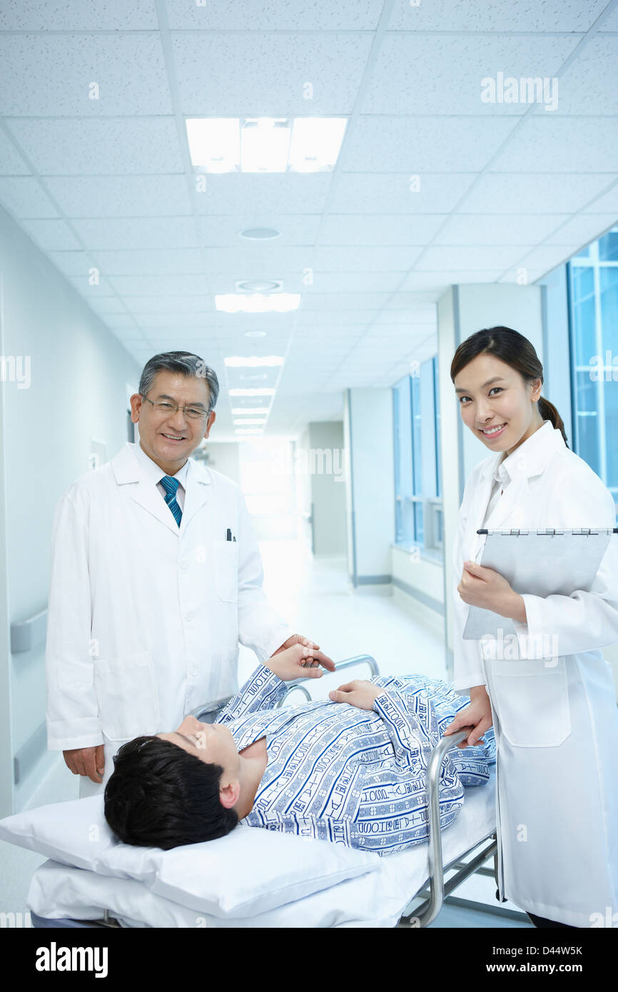 a patient lying on a bed between doctors Stock Photo - Alamy