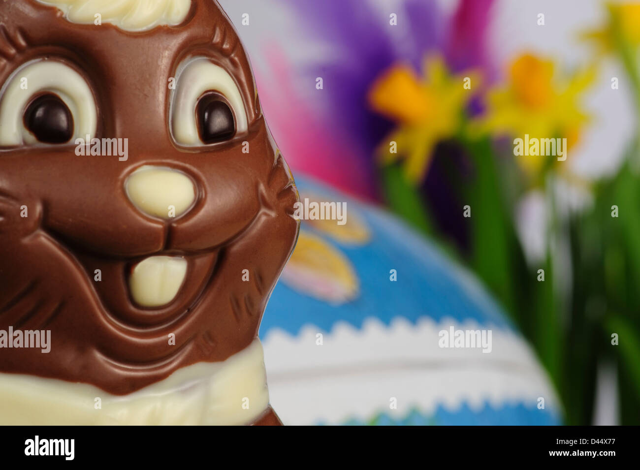 Easter bunny made of chocolate with daffodils and an easter egg in the background Stock Photo