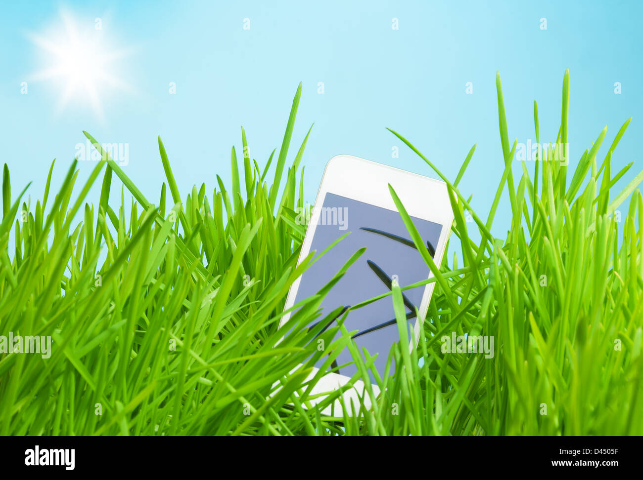 Brand new device - touch screen cell phone in grass depicting spring sale concept Stock Photo