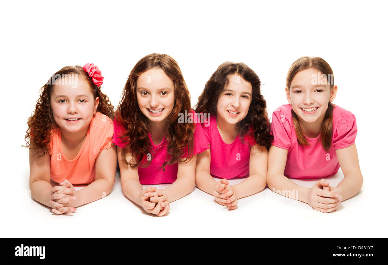 Four cute teen girls in pink laying on the floor, smiling and look happy, isolated on white Stock Photo