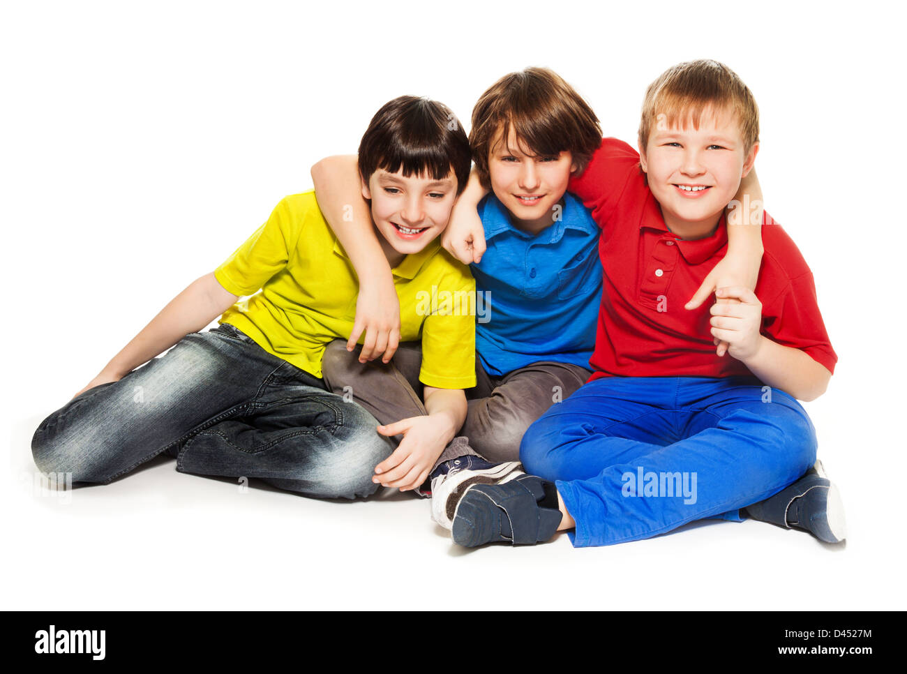 Three boys friends sitting on the floor, hugging, smiling and look happy, isolated on white Stock Photo