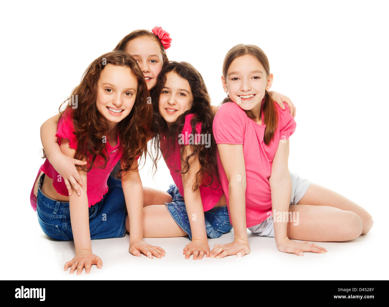 Four cute 10 years old girls in pink sitting, smiling and look happy, isolated on white Stock Photo