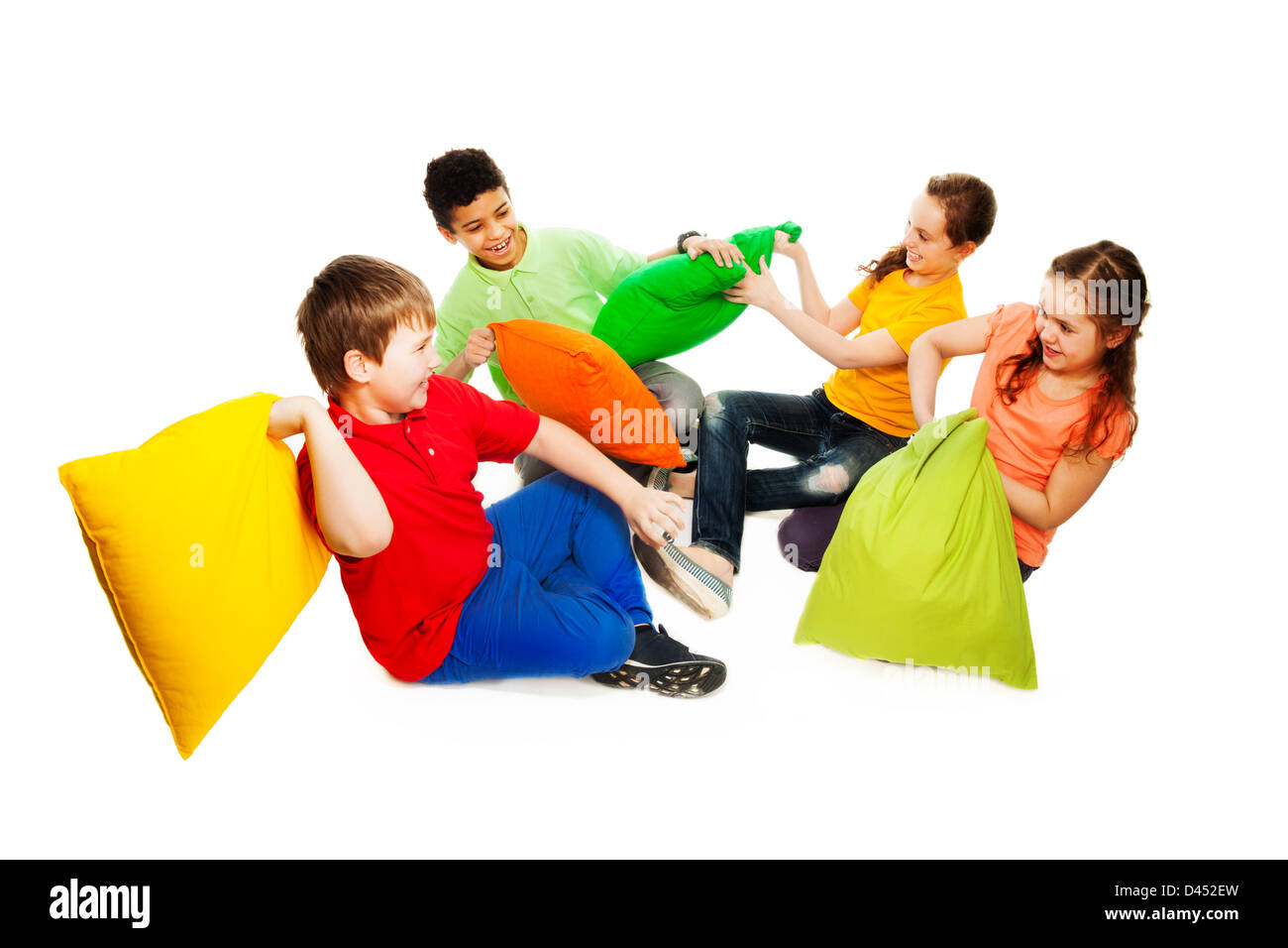 Cute four teen kids, boys and girls fighting with pillows, laughing, smiling and having fun, isolated on white Stock Photo
