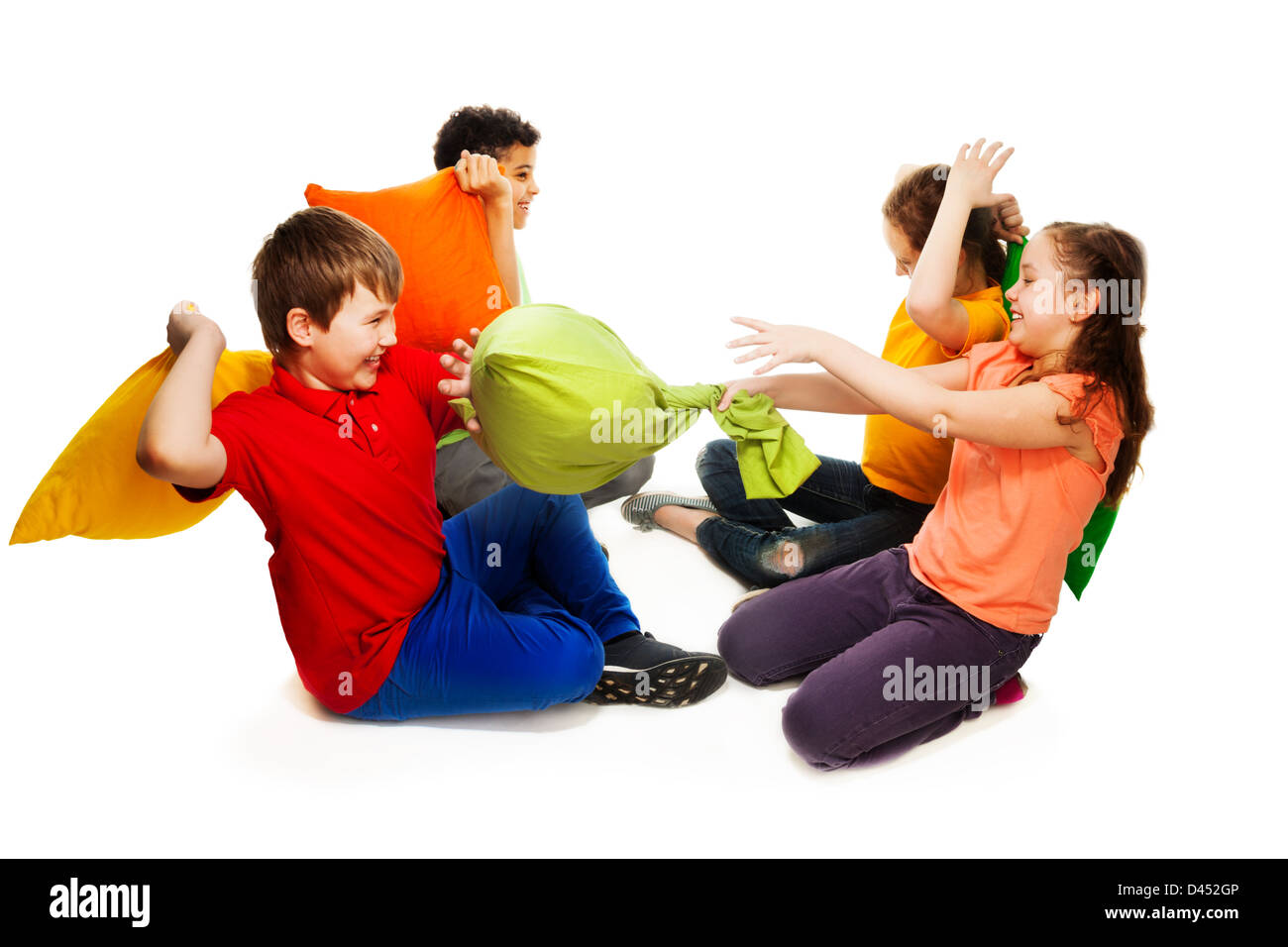 Cute four teen kids, boys and girls fighting with pillows, laughing and having fun, isolated on white Stock Photo