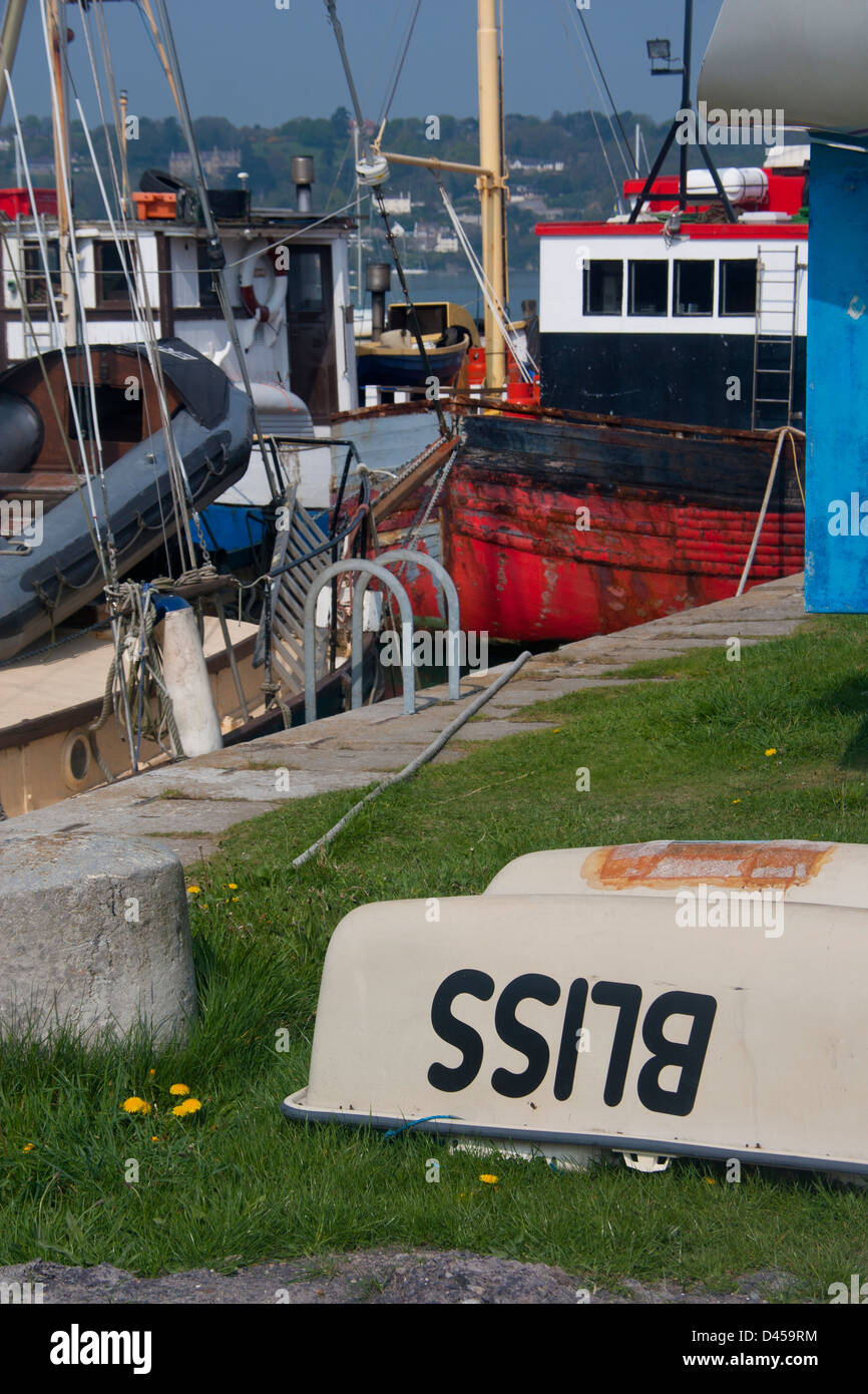 Porth Penrhyn harbour in Bangor Gwynedd Wales UK Upturned boat named 'Bliss' with fishing boats along quayside in background Stock Photo