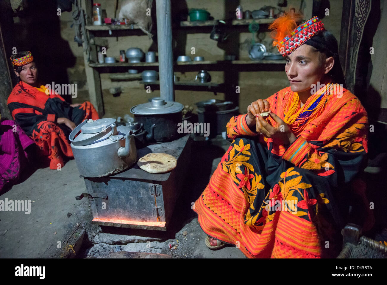 Kalash woman eating breakfast in her house, Balanguru, Rumbur Valley, Chitral, Khyber-Pakhtunkhwa, Pakistan Stock Photo