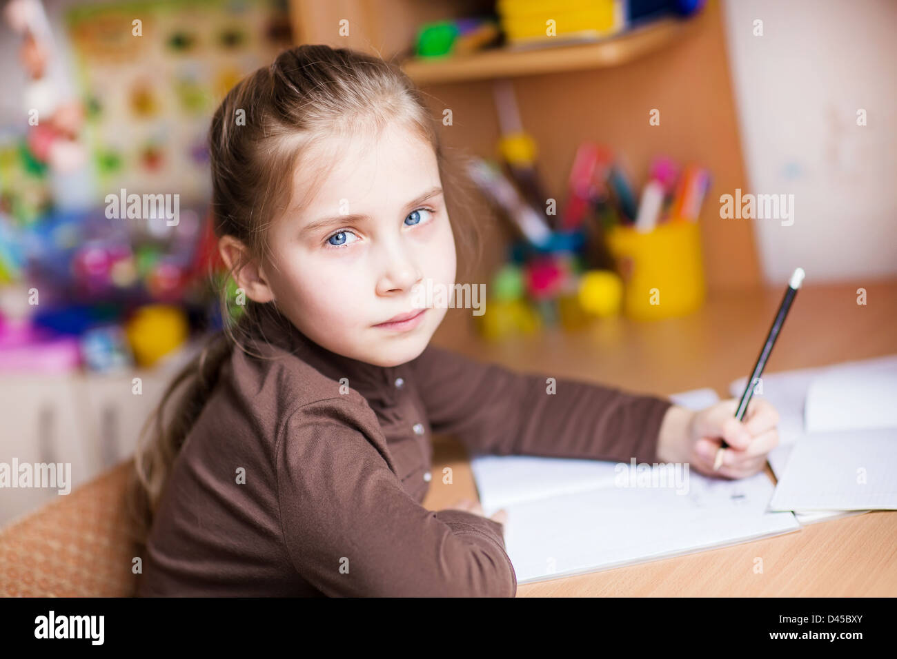 Cute little girl writing her homework at the table Stock Photo Alamy