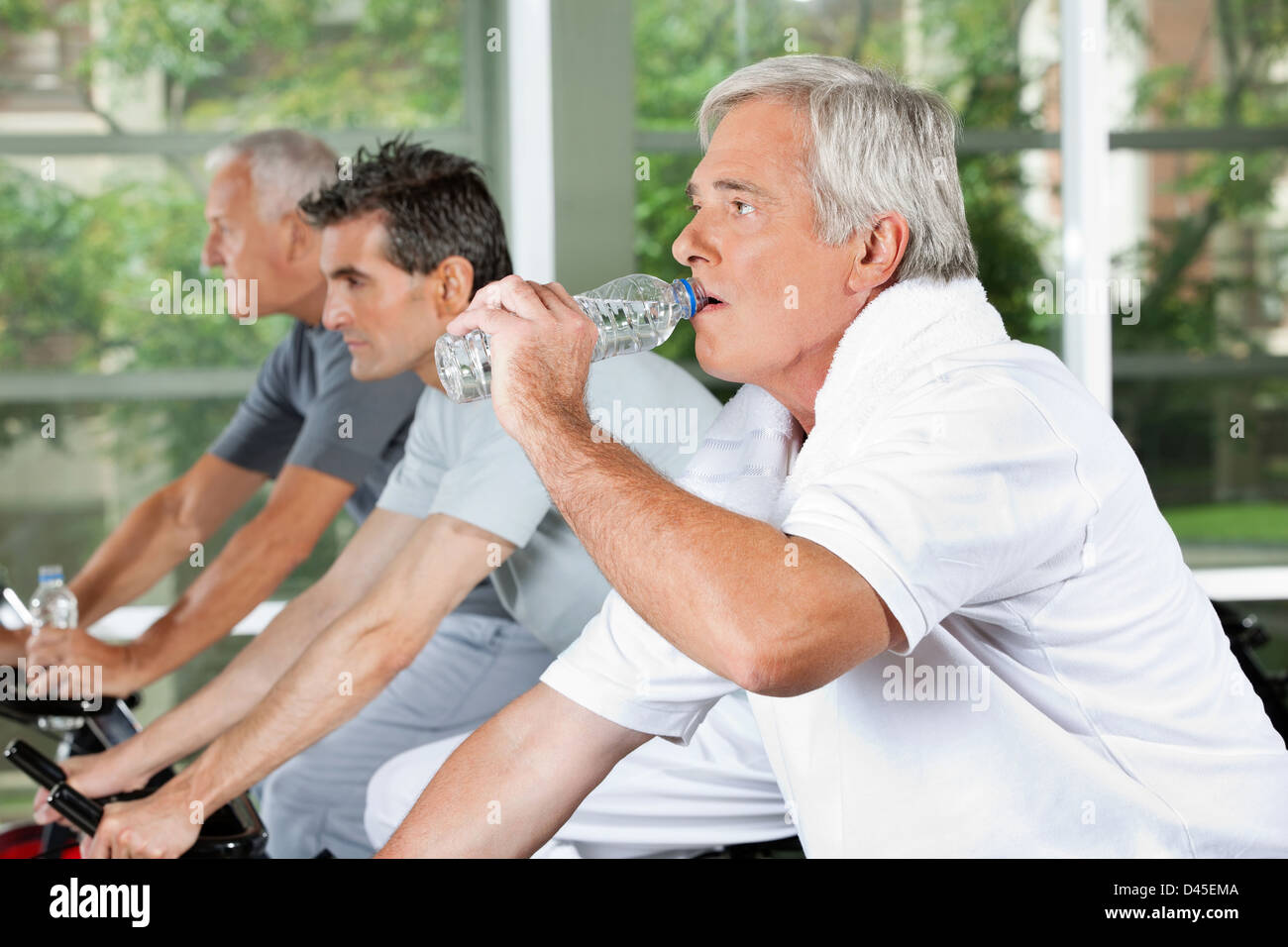 Elderly man in fitness center drinking water from a plastic bottle Stock Photo