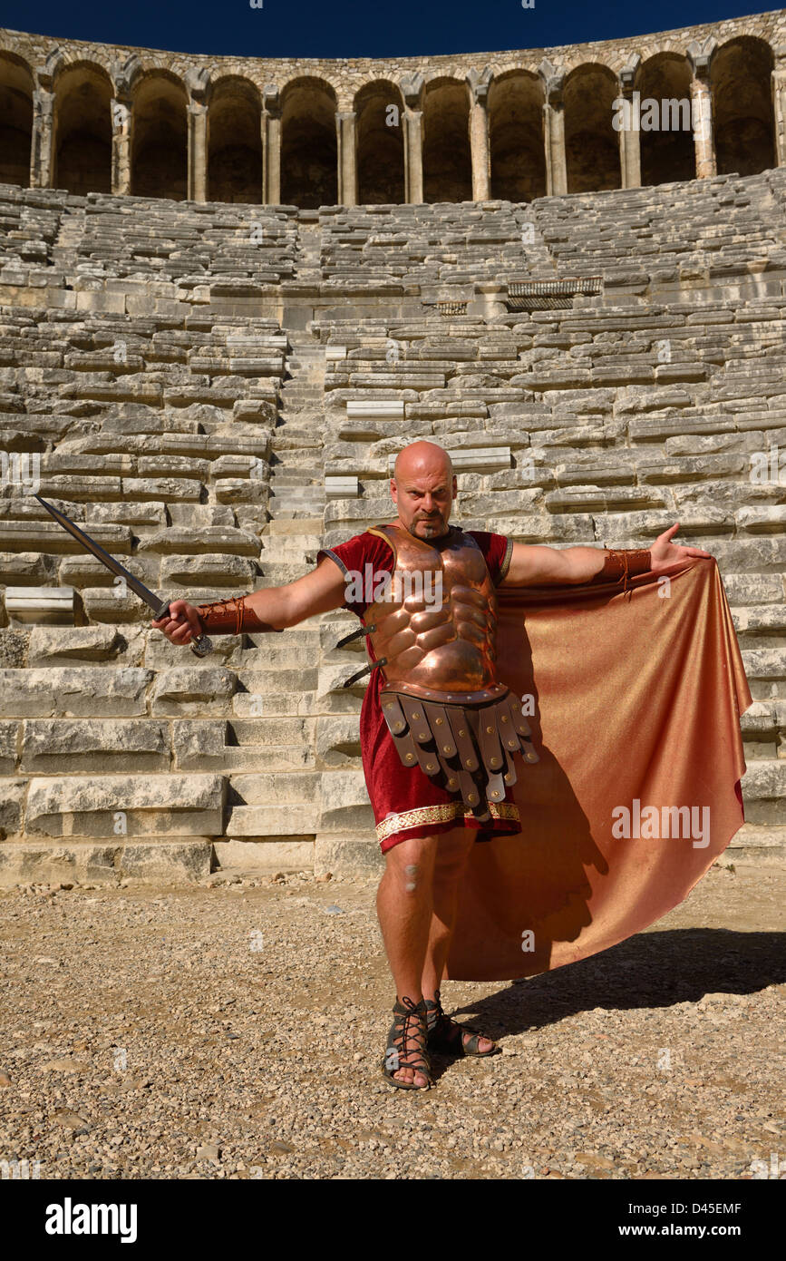 Roman Gladiator with sword spreading cape in sun on stage at the ancient Aspendos Roman theatre ruins Turkey Stock Photo