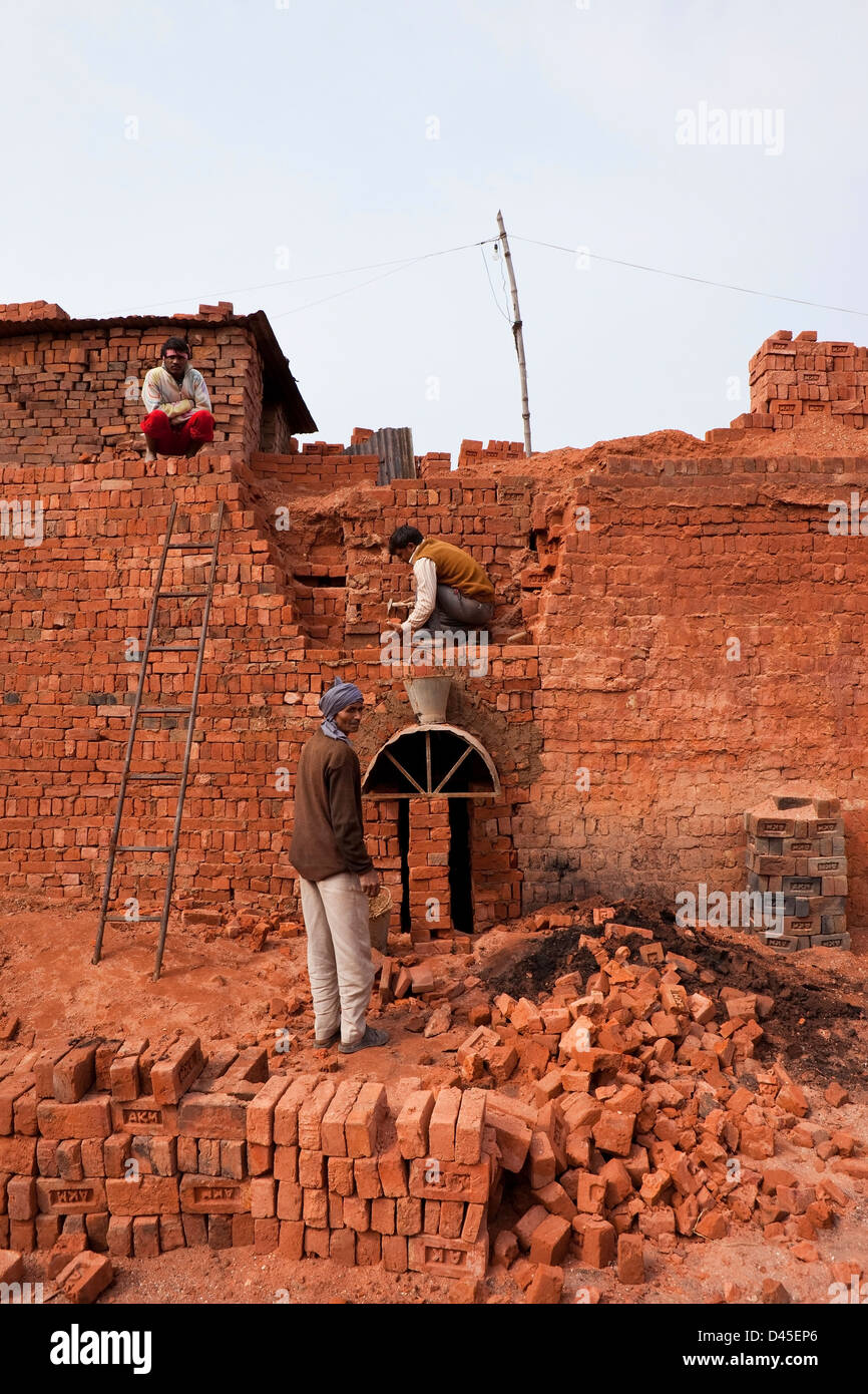 A  traditional Punjabi brickworks with three workers removing bricks after firing. Stock Photo