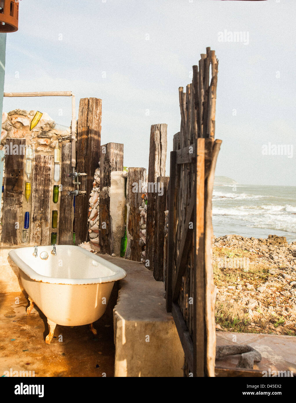 A bath tub and a wooden fence near the ocean shore. Stock Photo
