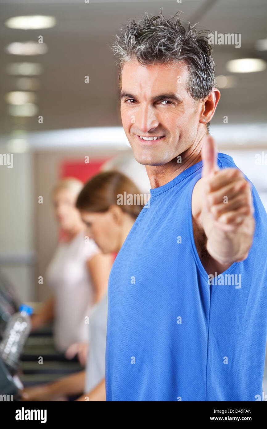 Man on treadmill holding his thumbs in up in gym Stock Photo - Alamy