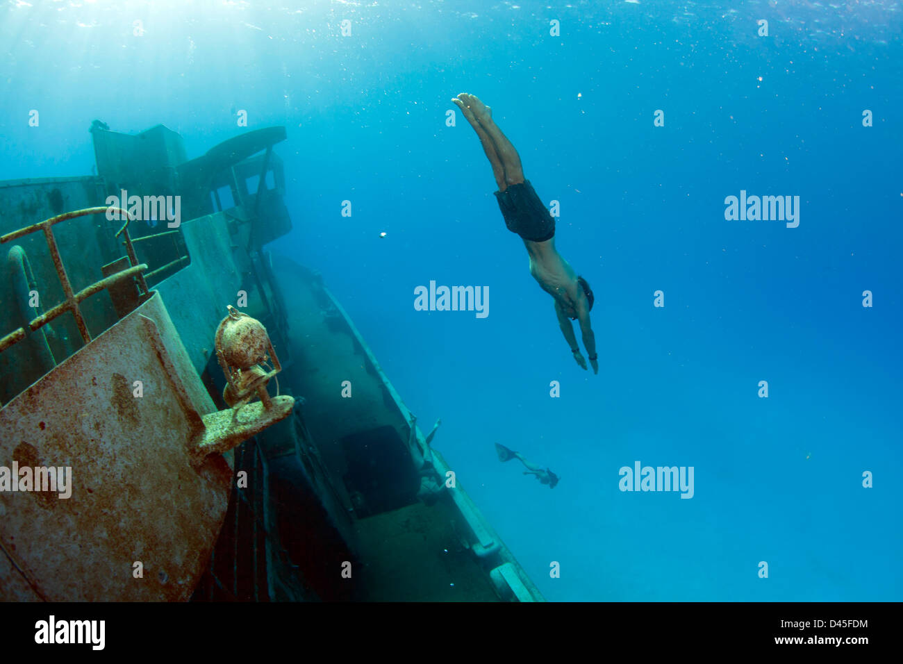 A freediving man 'jumps' off the side of the Kittiwake Shipwreck off Grand Cayman Island. Stock Photo