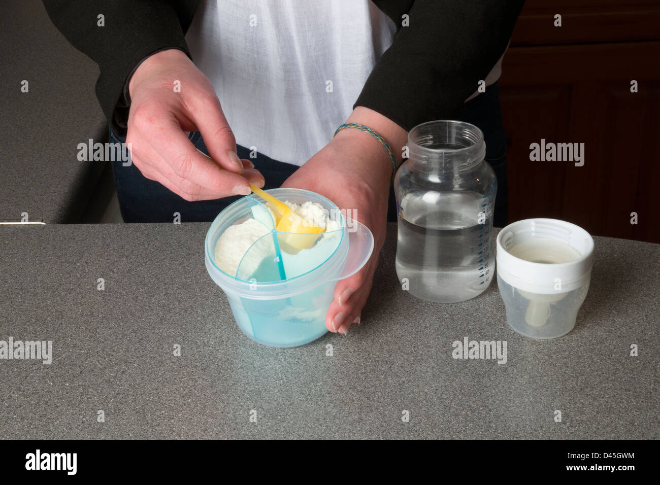 Young mother's hands preparing powdered milk drink for her baby Stock Photo