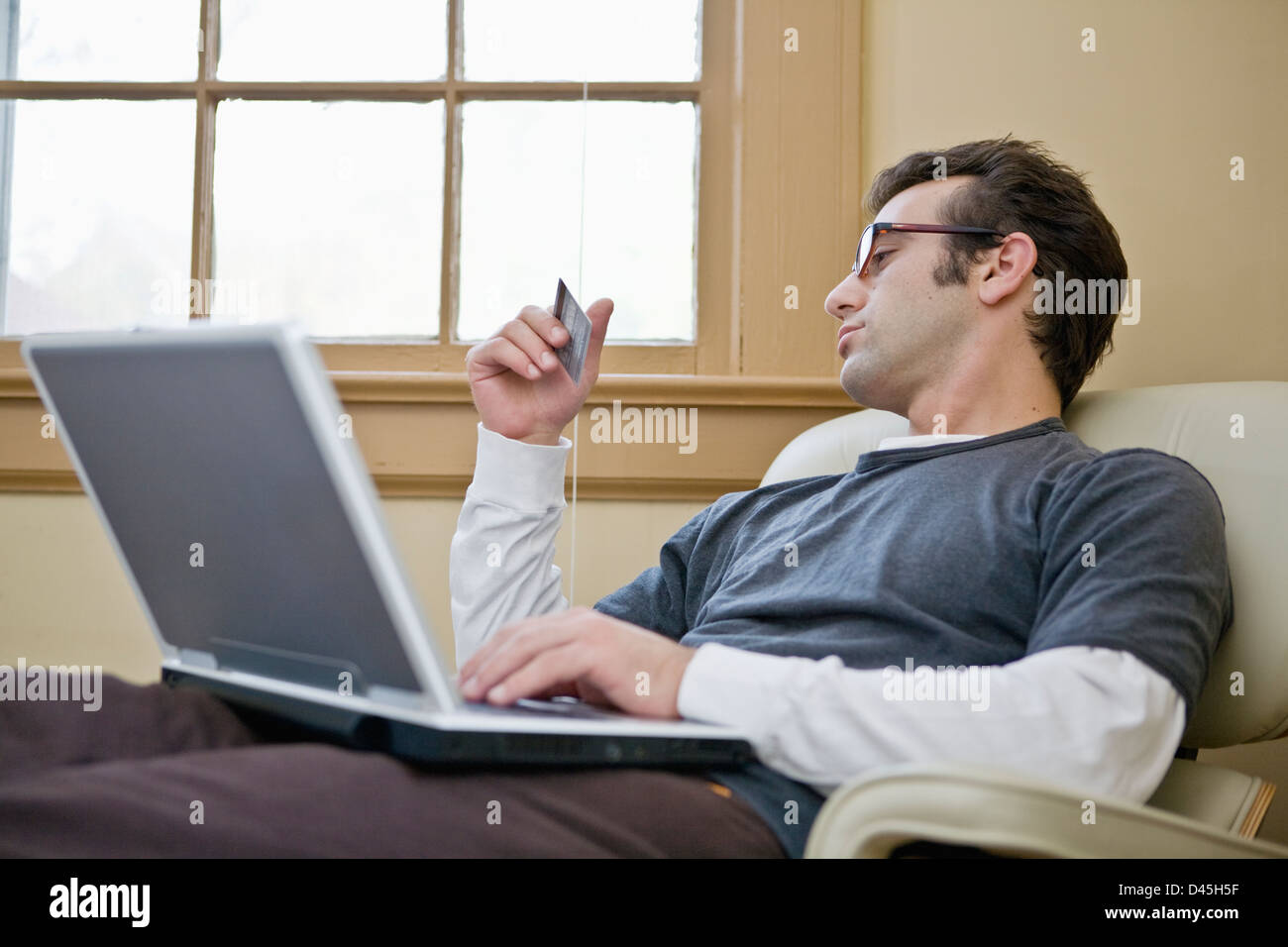 Relaxed Man With Glasses Shopping Online Using Credit Card Stock Photo