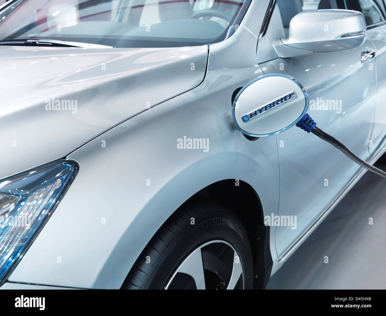 License available at MaximImages.com - Plug-in hybrid electric vehicle recharging batteries at a charging station. Closeup of car power socket lid. 20 Stock Photo