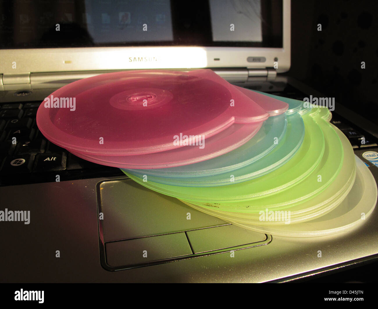 Stack of coloured plastic CD cases on laptop Stock Photo