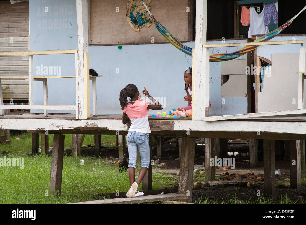 Two girls talking to each other on the porch of a home on stilts Stock ...
