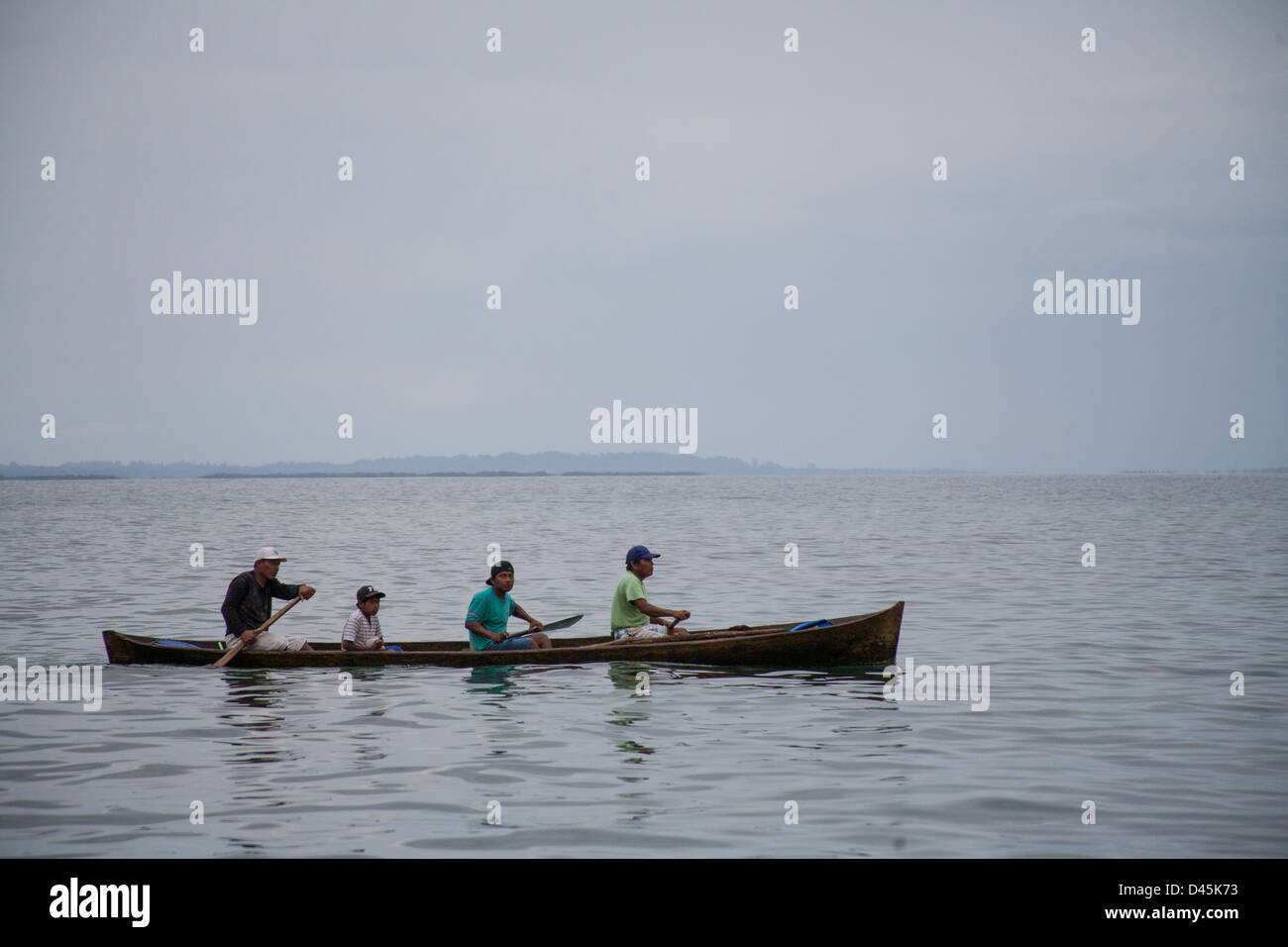 Panamanians rowing a traditional wooden cayuco in the Caribbean Sea. Stock Photo