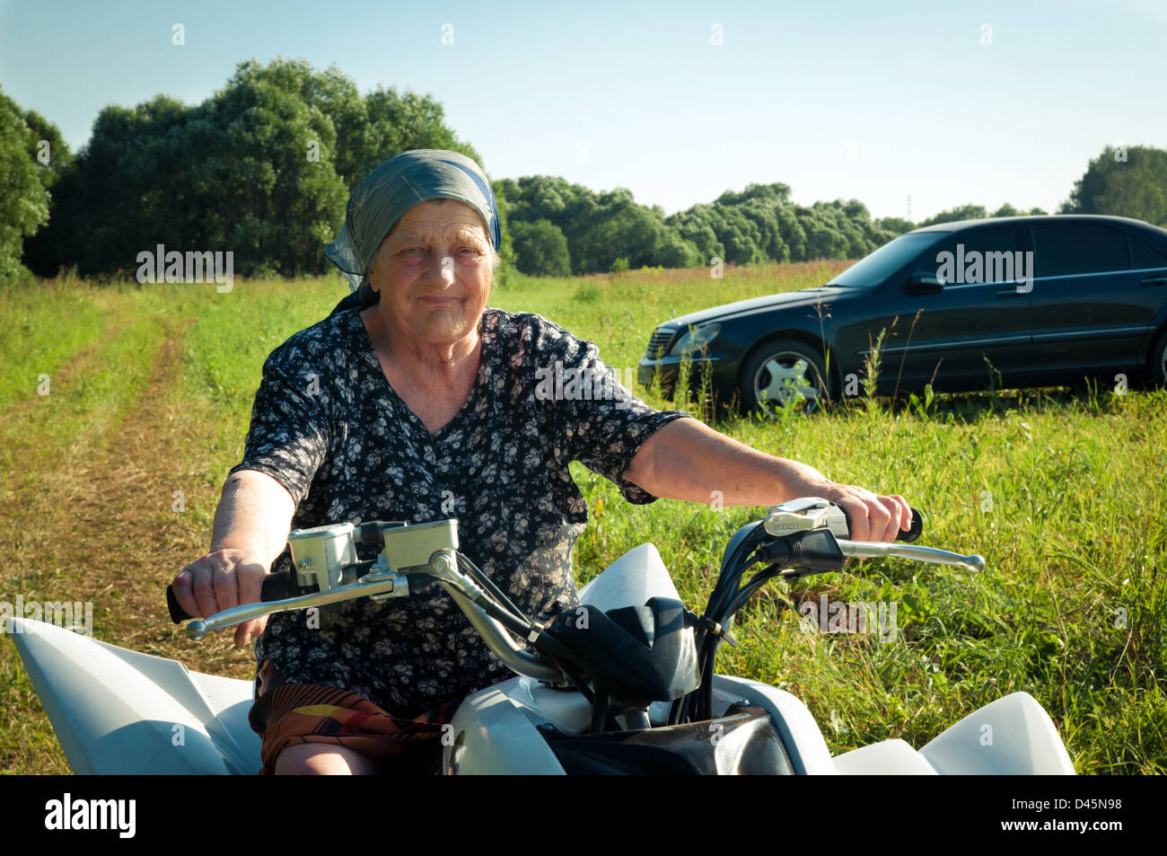 The old woman on an ATV Yamaha Raptor 350 and Merсedes-Benz S-Class (W220) Stock Photo