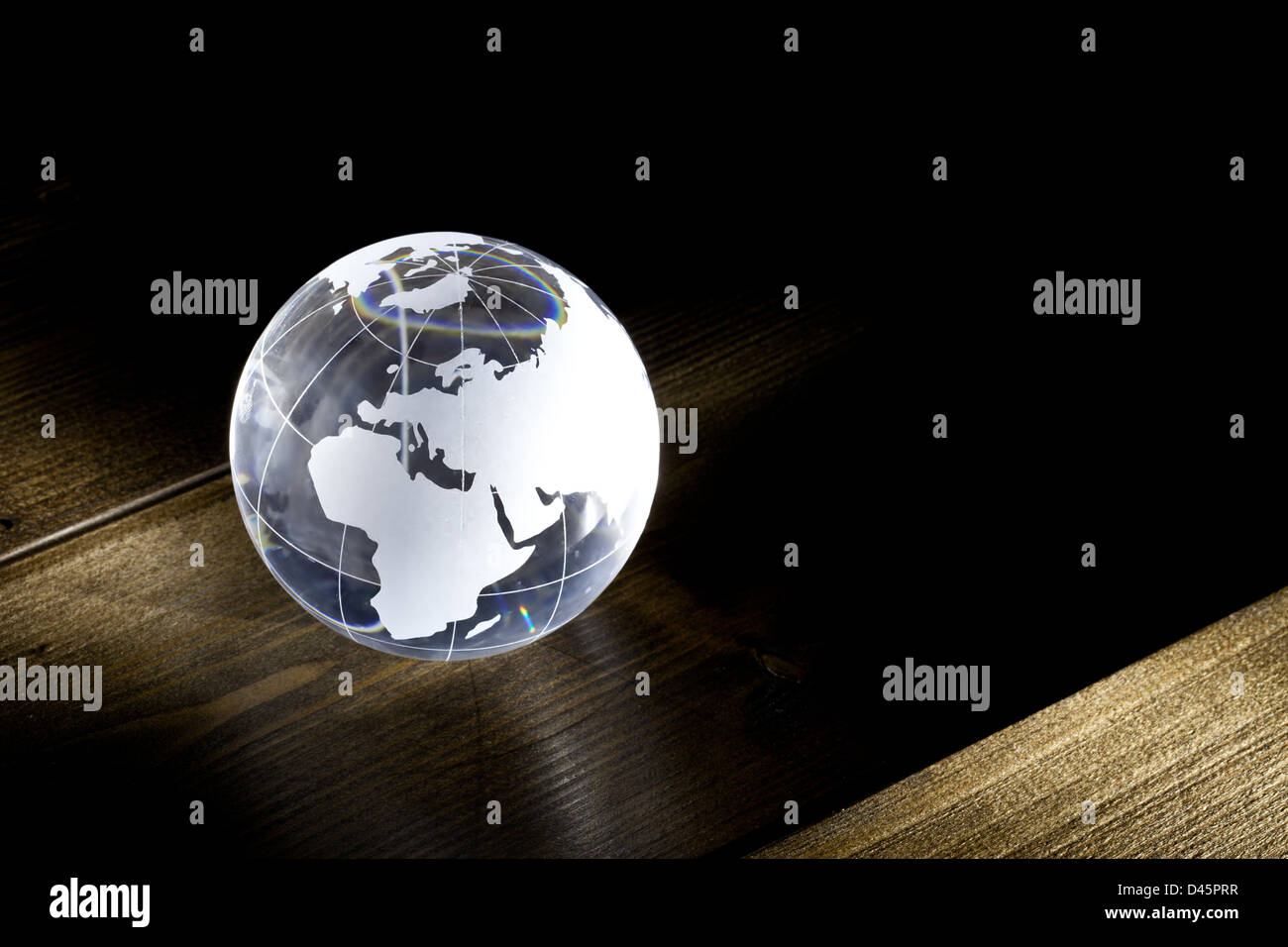 Glass earth globe on a wooden table with light Stock Photo