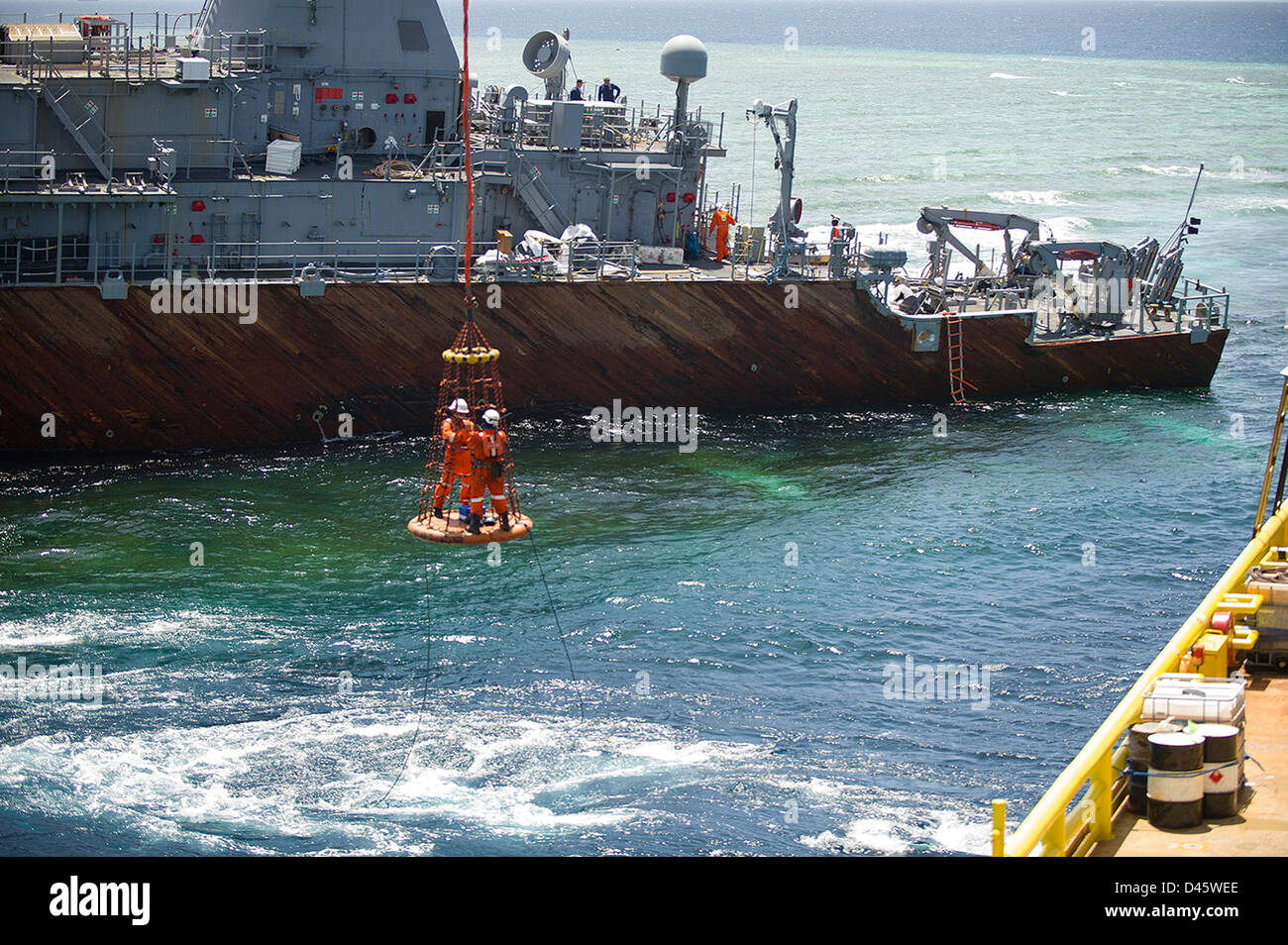 Salvage crew members are craned to USS Guardian. Stock Photo