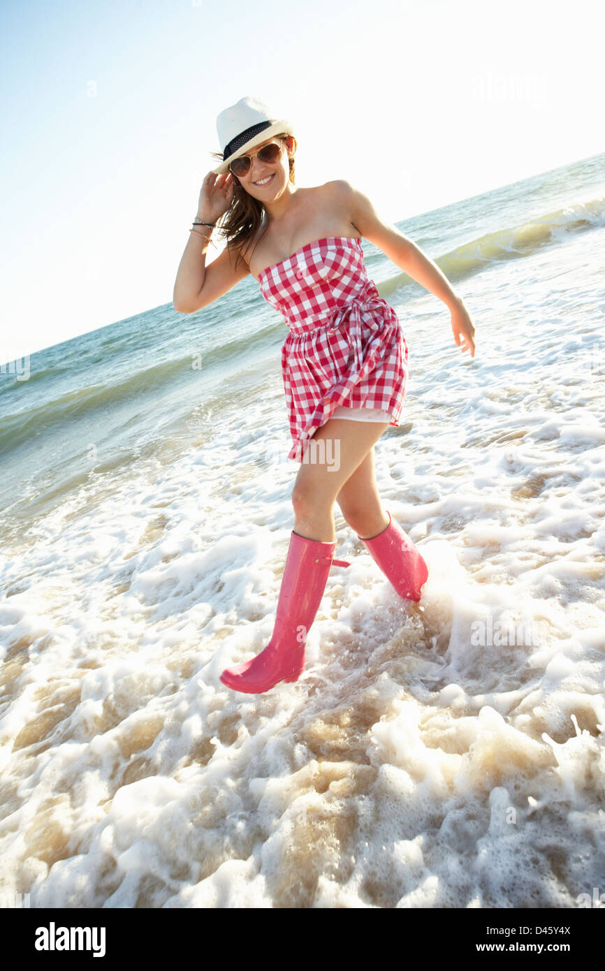 Teenage Girl Wearing Wellington Boots Splashing In Sea On Beach Holiday Stock Photo Alamy