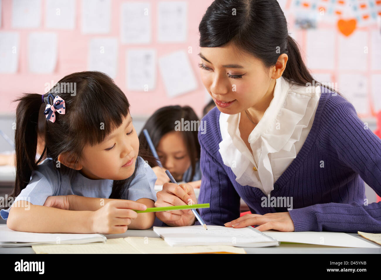 Teacher Helping Student Working At Desk In Chinese School Classroom Stock Photo Alamy