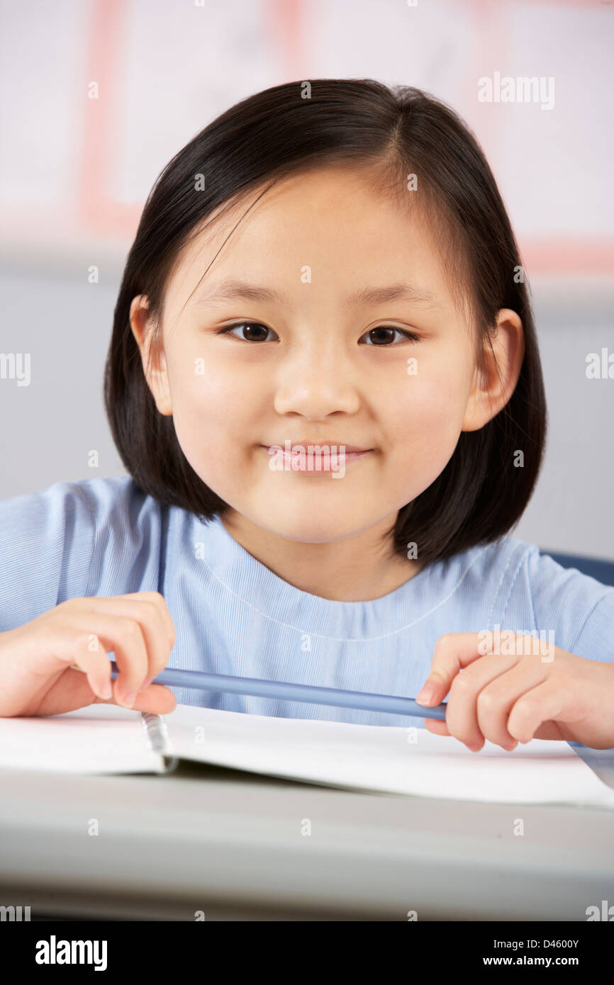 Female Student Working At Desk In Chinese School Classroom Stock Photo