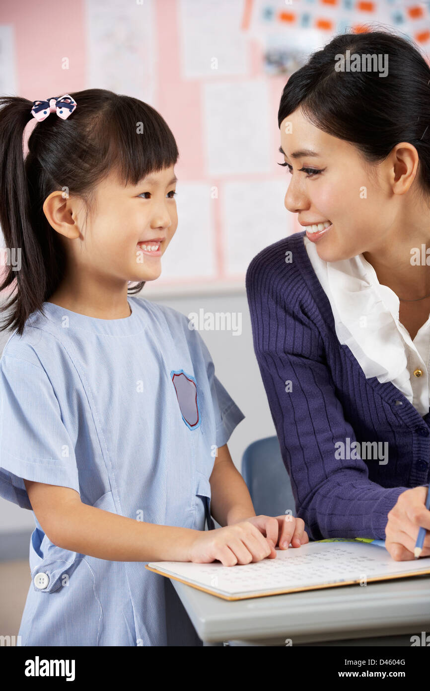 Teacher Helping Student Working At Desk In Chinese School Classroom Stock Photo Alamy