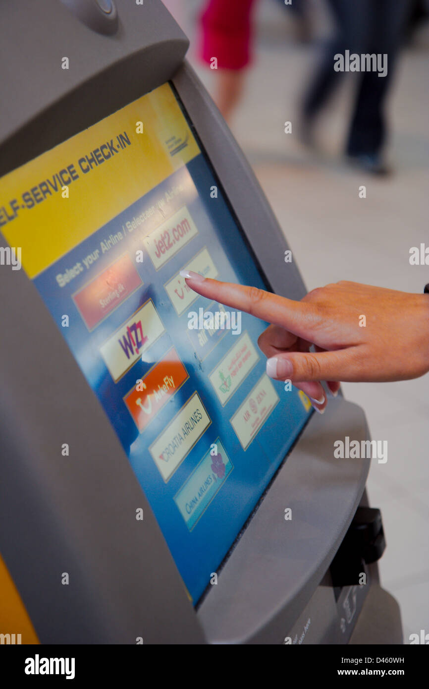 Finger touching Check-in Display on Schiphol Airport Stock Photo