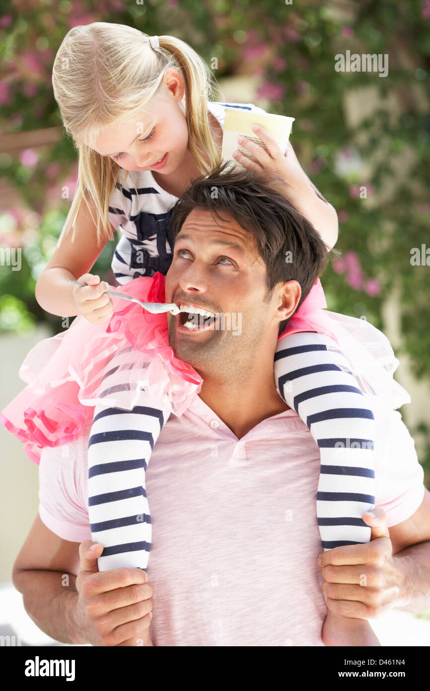 Father Giving Daughter Ride On Shoulders Outdoors Whilst Eating Marshmallows Stock Photo