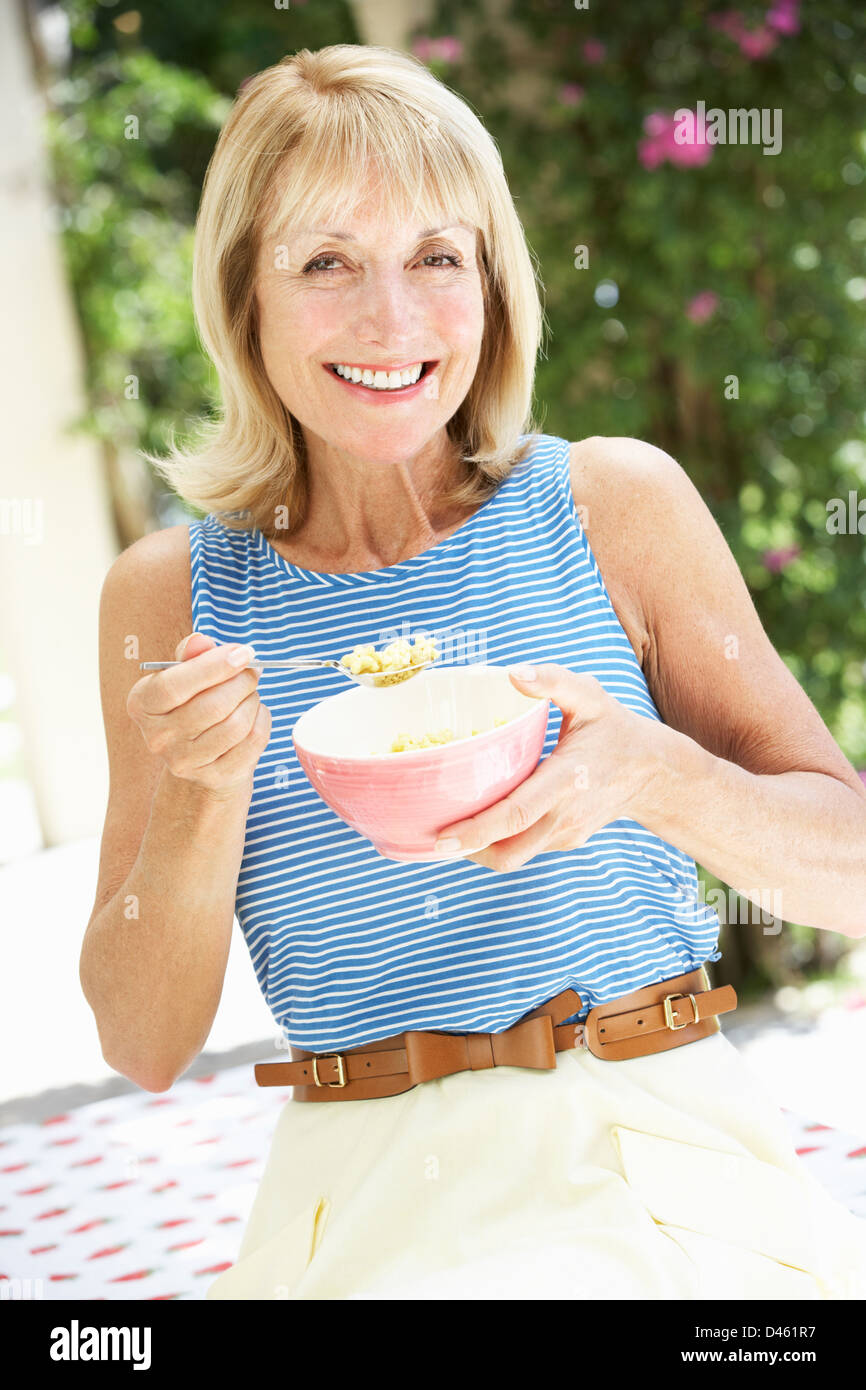 Senior Woman Enjoying Bowl Of Breakfast Cereal Stock Photo